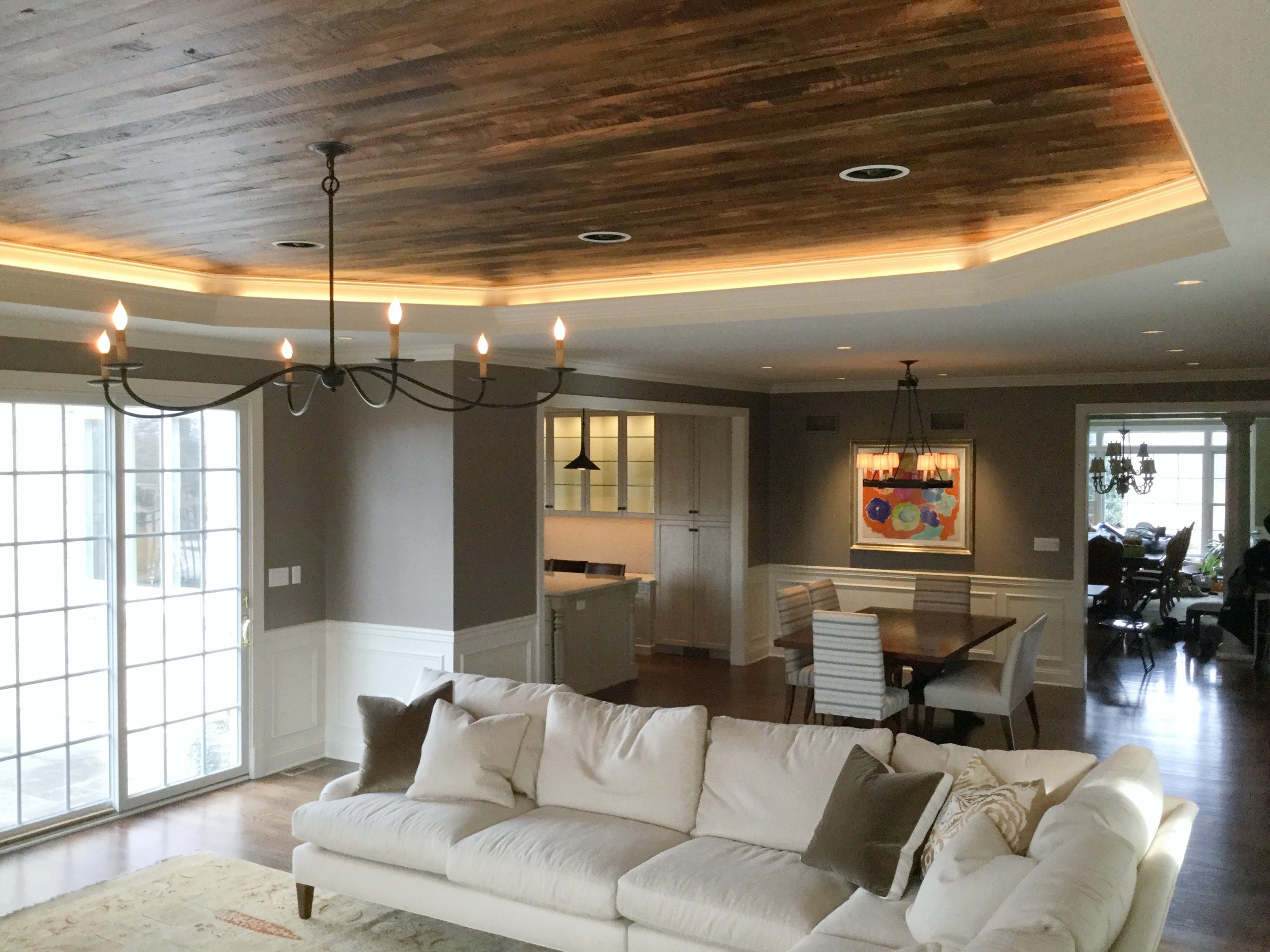 Transitional family and dining room with black metal chandelier and beige furniture (Hardwood ceiling angle)