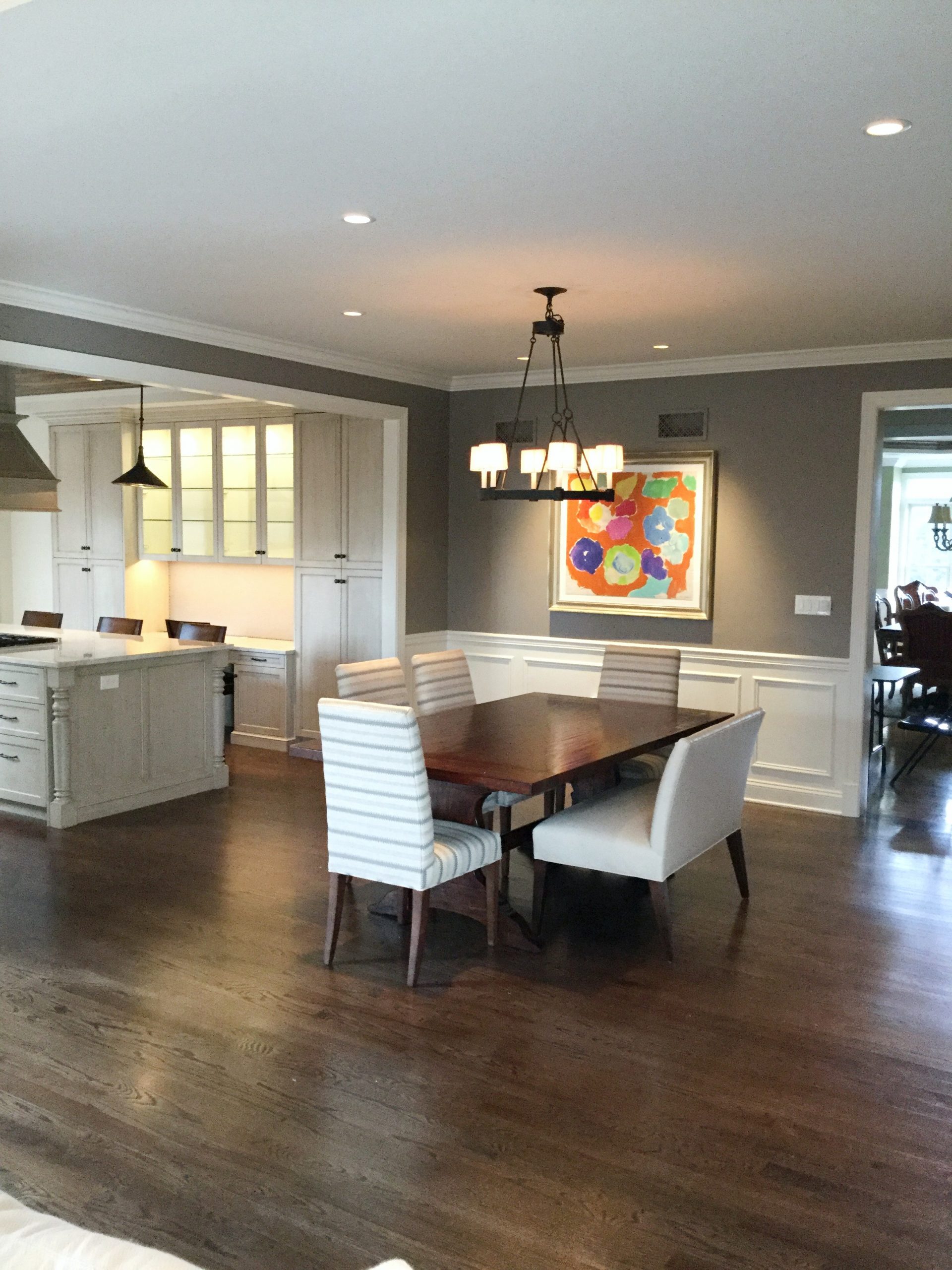 Transitional dining room with dark hardwood flooring and table, striped accented dining chairs, and light beige bench (Zoomed out)