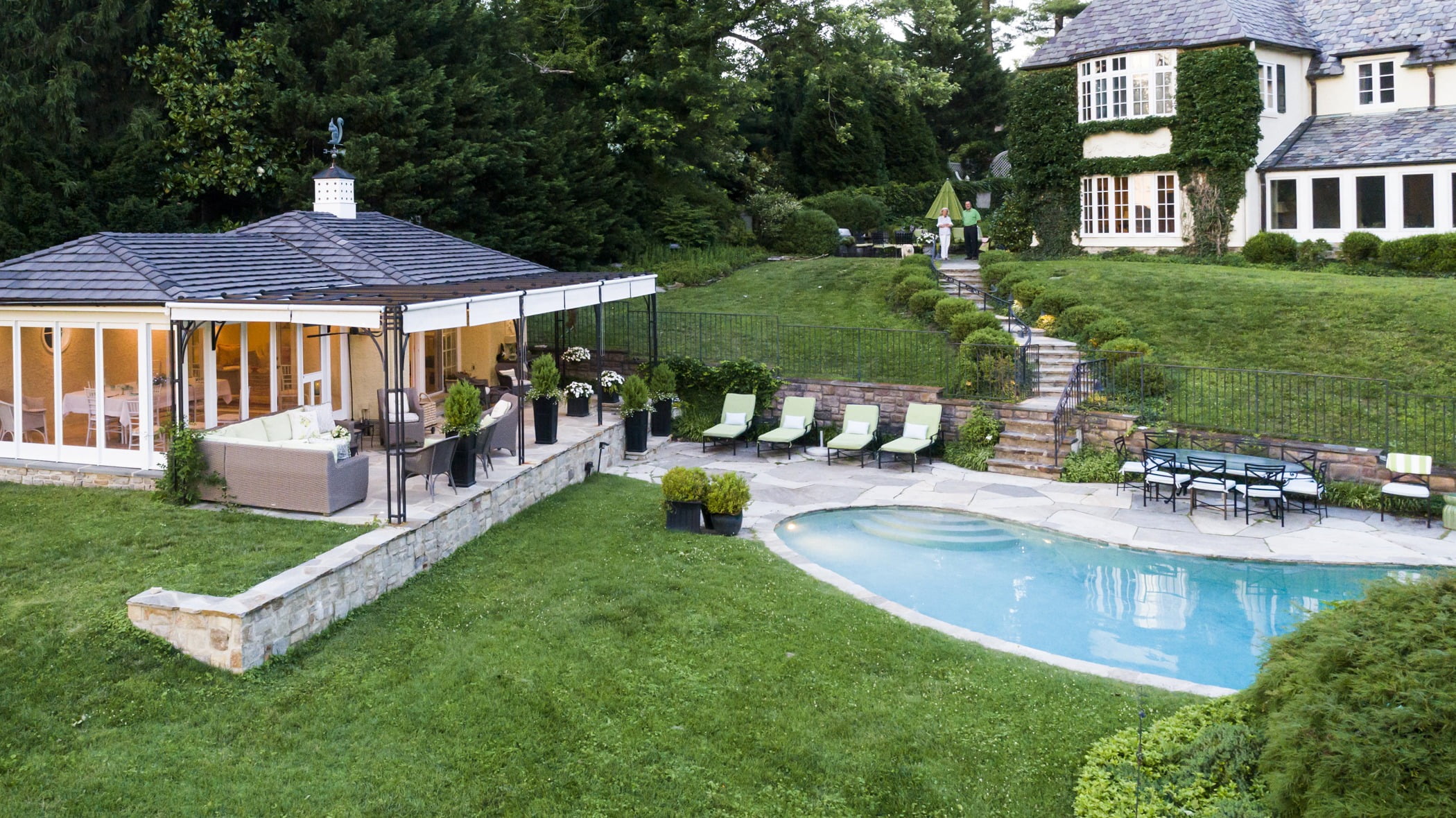 Luxury pool house custom designed for a home remodel with a large seating space and large metal pergola (Side and pool view)