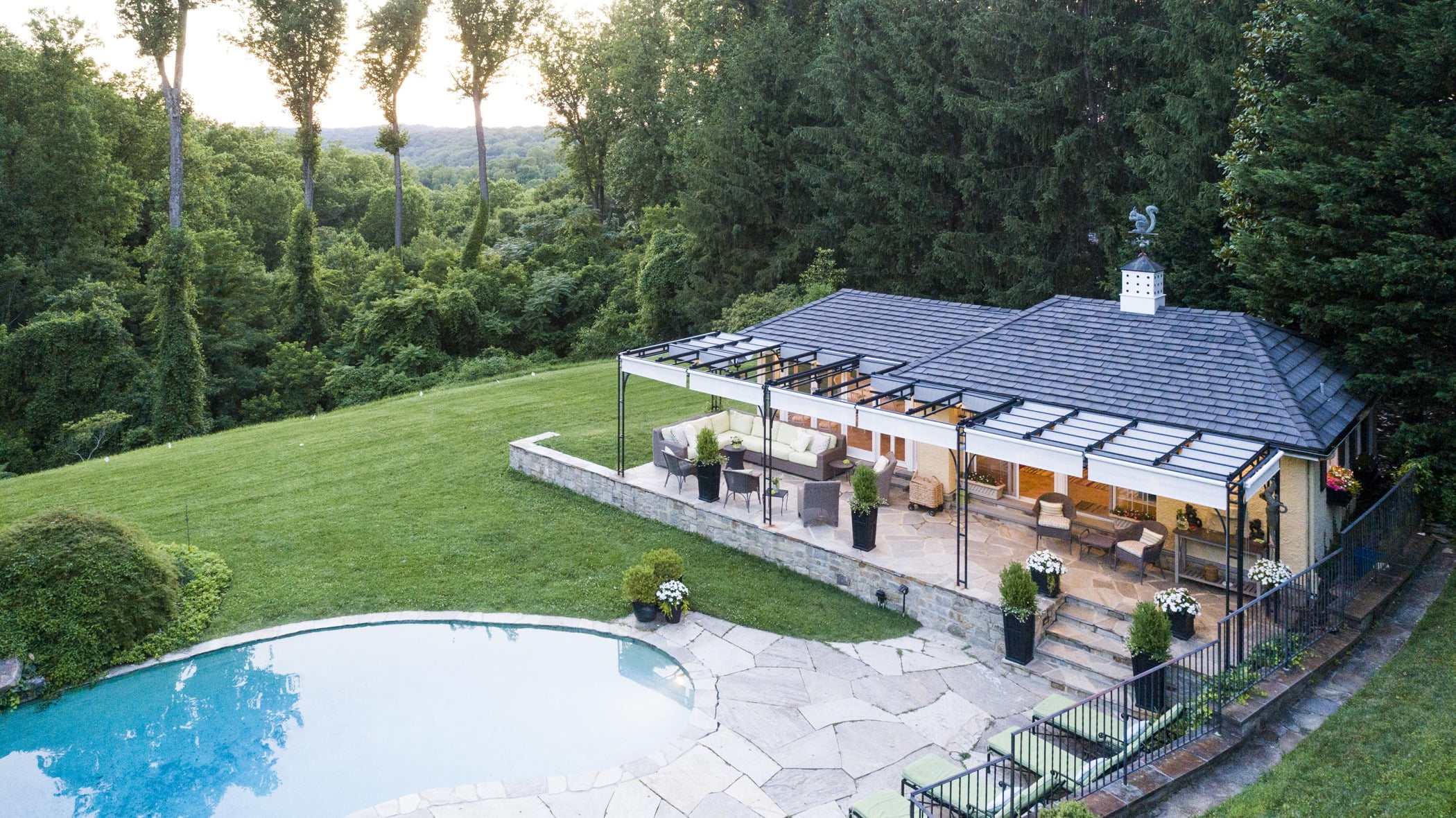 Luxury pool house custom designed for a home remodel with a large seating space and large metal pergola (Aerial view)