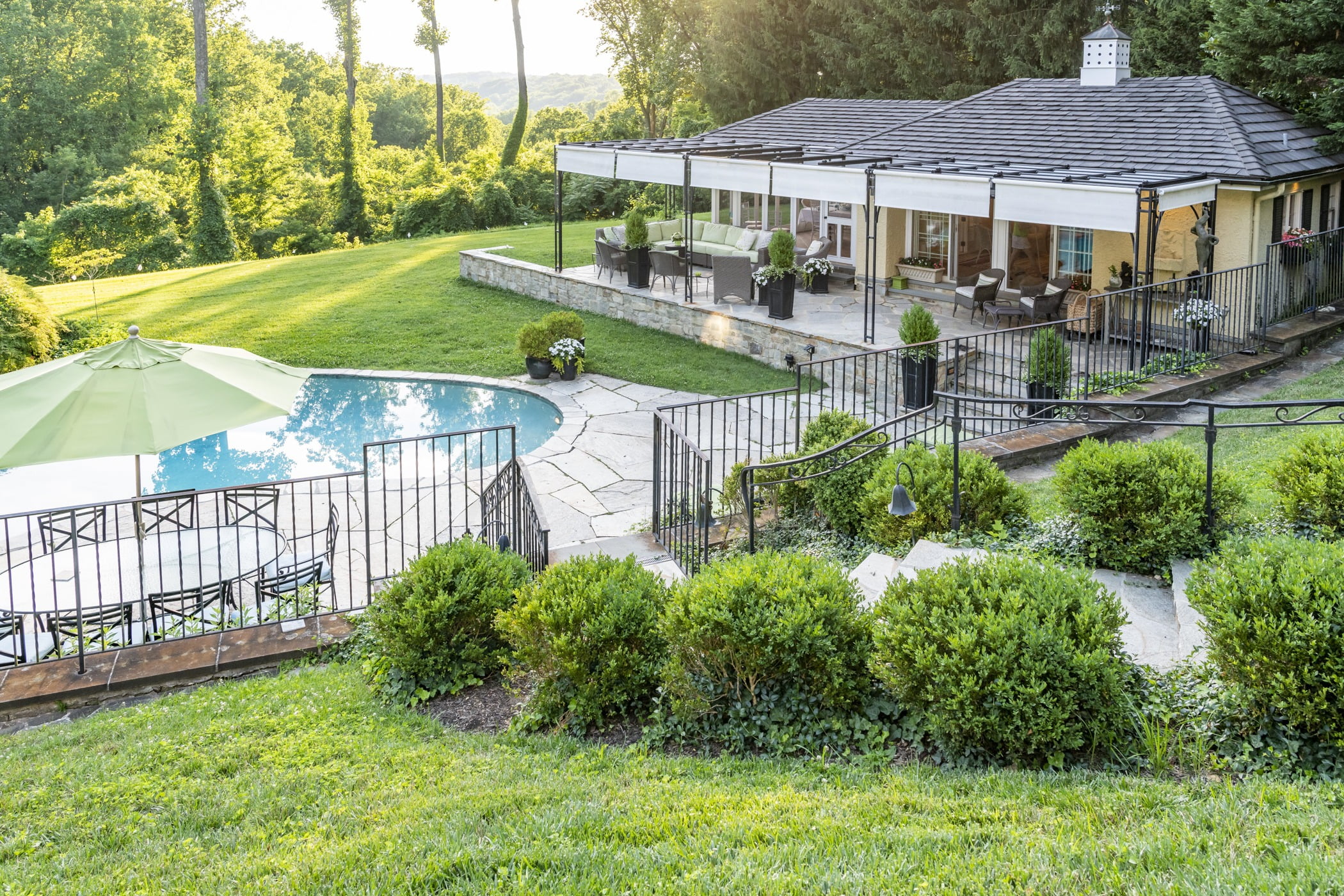 Luxury pool house custom designed for a home remodel with a large seating space and large metal pergola (House side view)