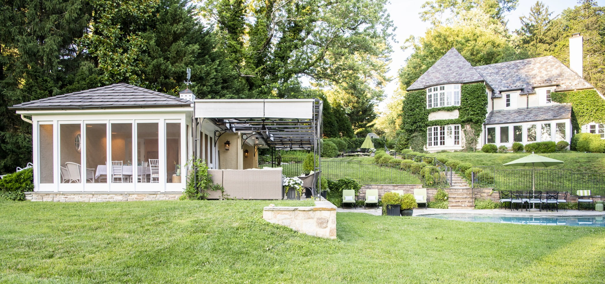 Luxury pool house custom designed for a home remodel with a large seating space and large metal pergola (side view)