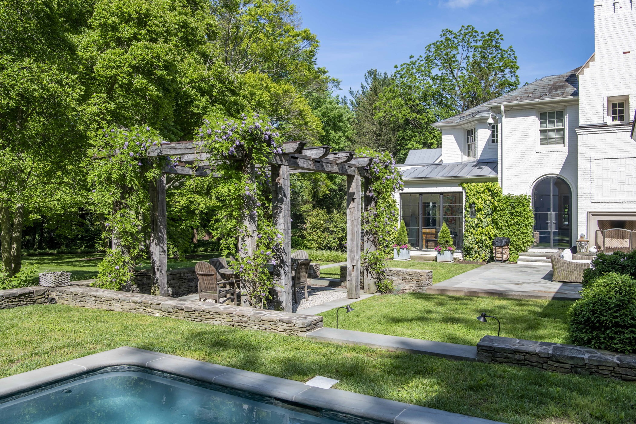 Ivy-covered wooden pergola, outdoor seating and dining area, and rest of backyard