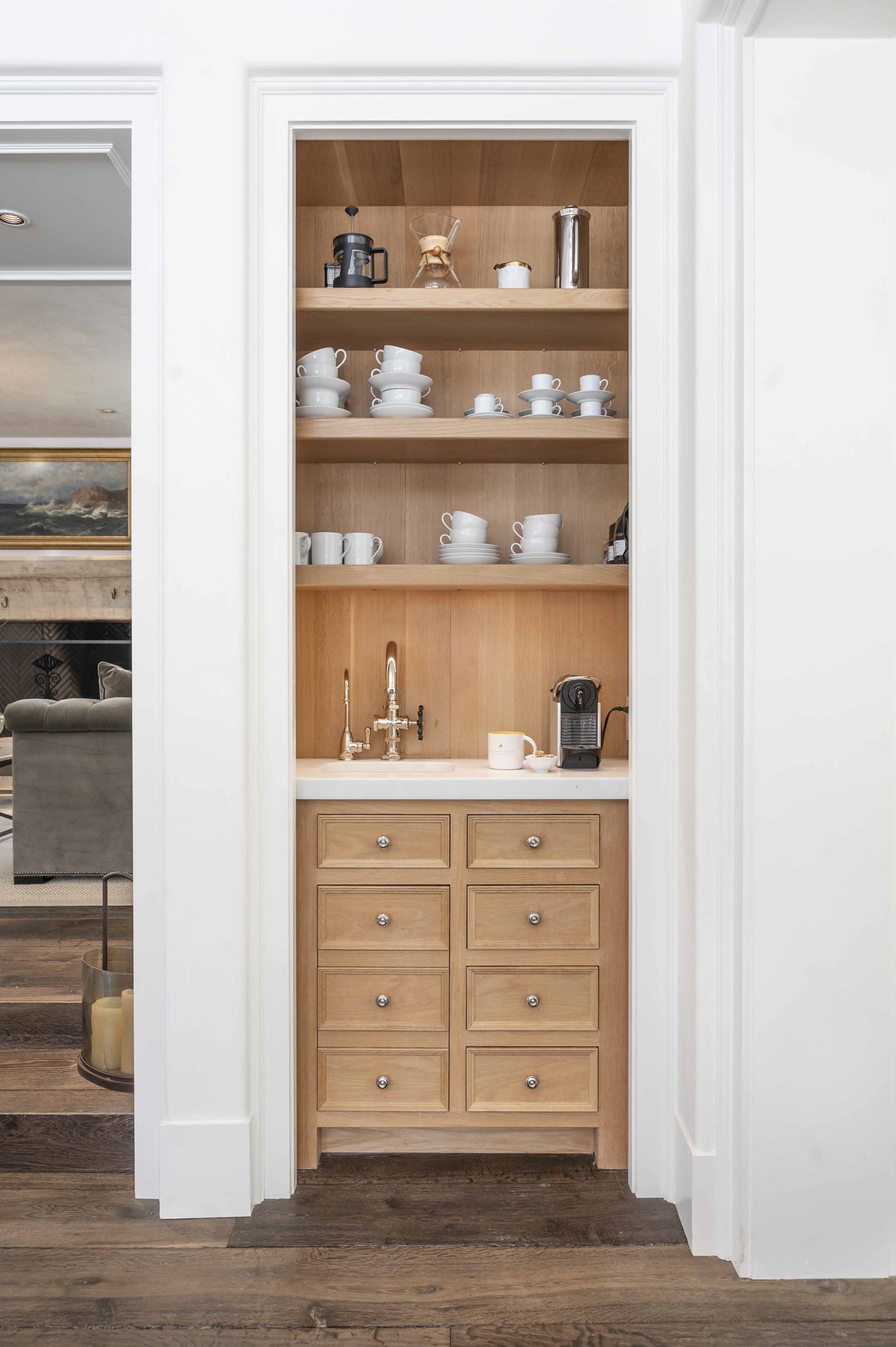 Transitional shelving space with light wood cabinetry and white marble countertops