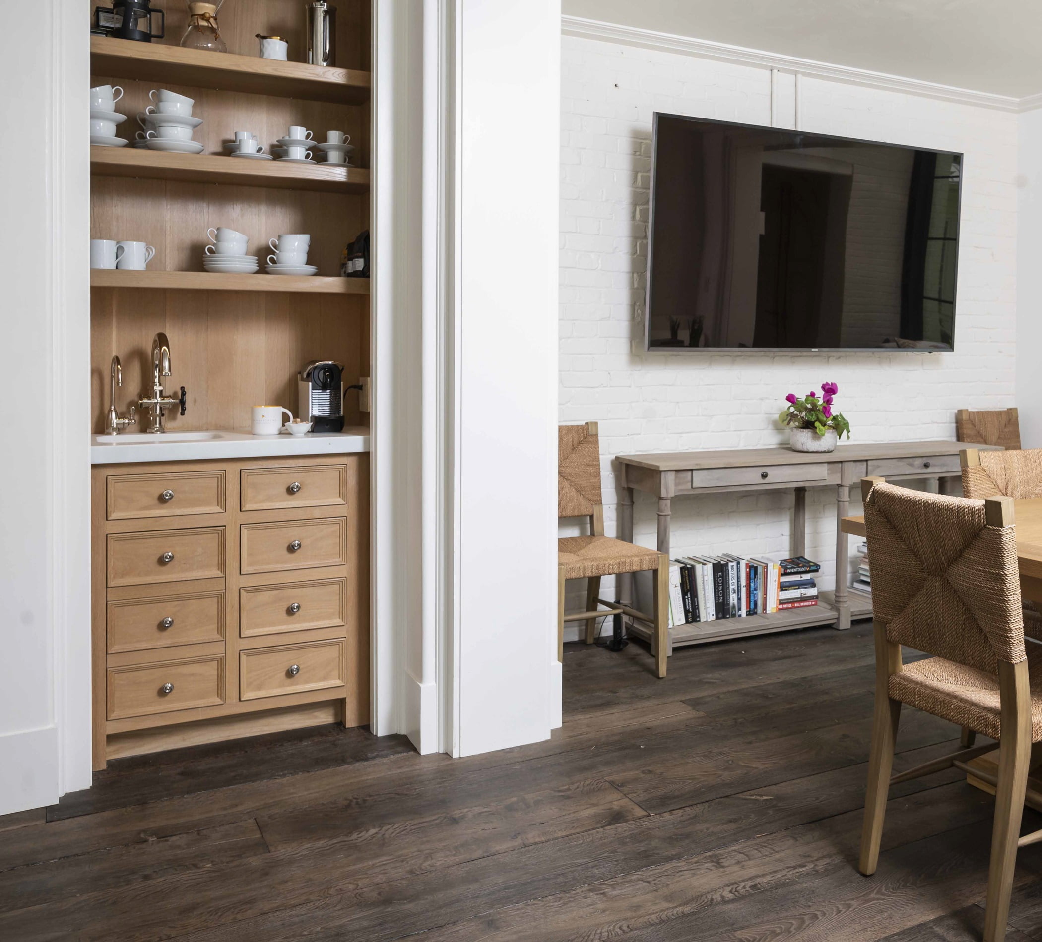 Transitional space with light wood cabinetry and white marble countertops, wicker chairs, and dark hardwood flooring