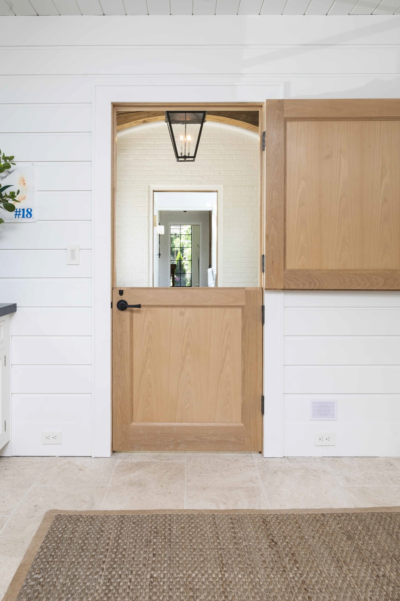 Transitional light hardwood interior dutch door with white panel walls and ceiling