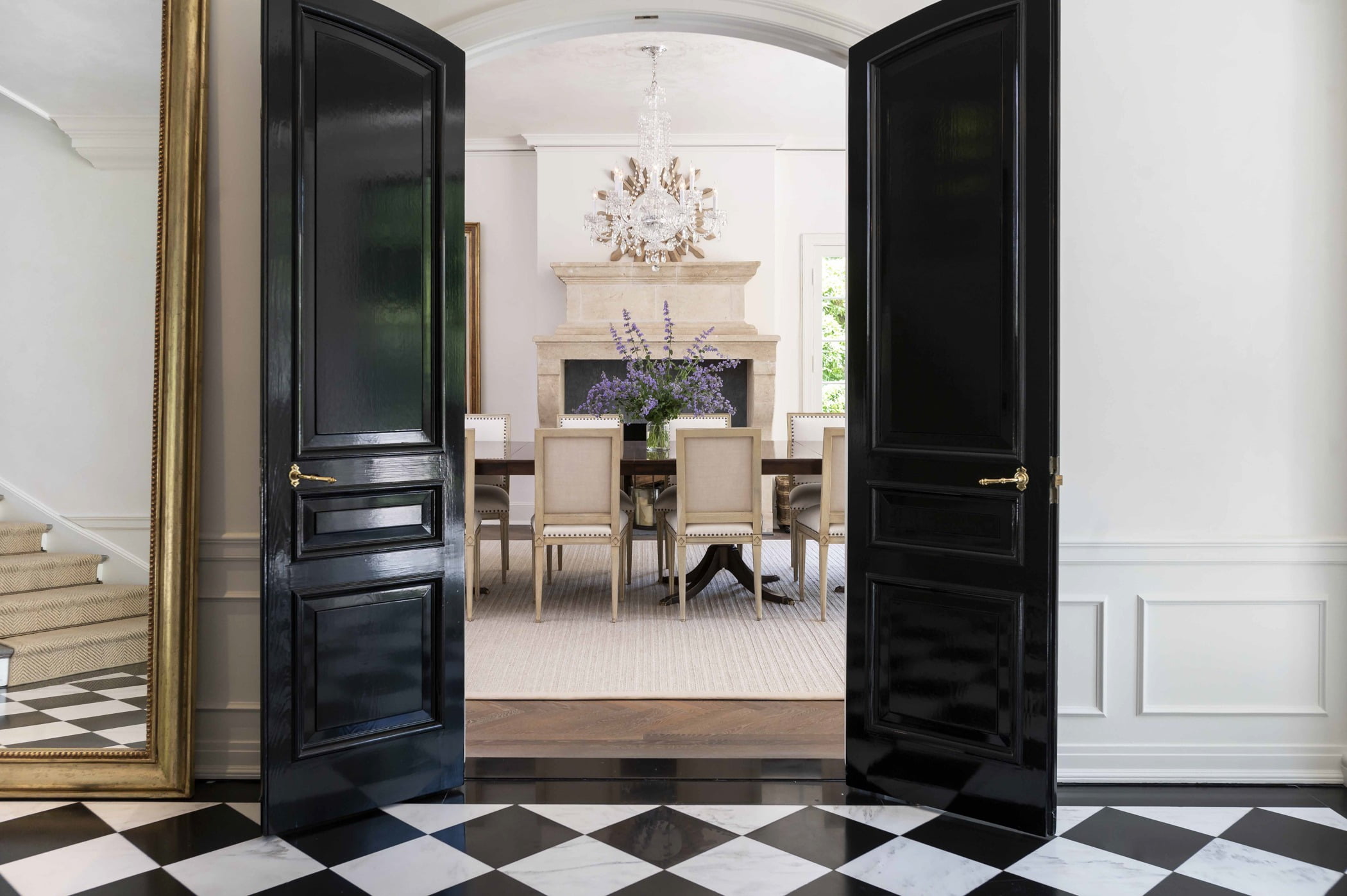 Traditional dining room through double arched black doors with black and white checkered tile flooring