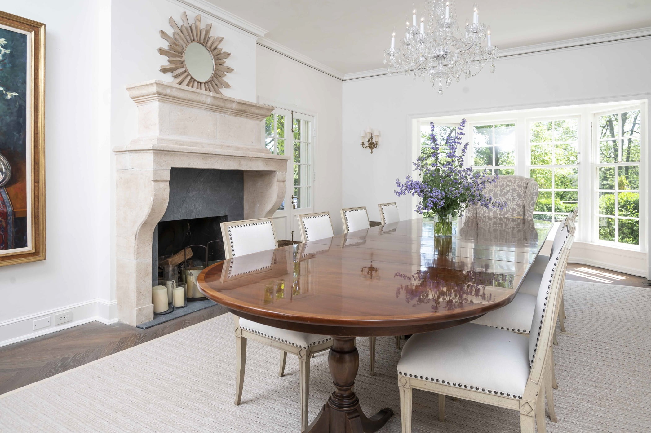 Traditional dining room with decorative stone fireplace, wood table, crystal chandelier and decorative cream color chairs