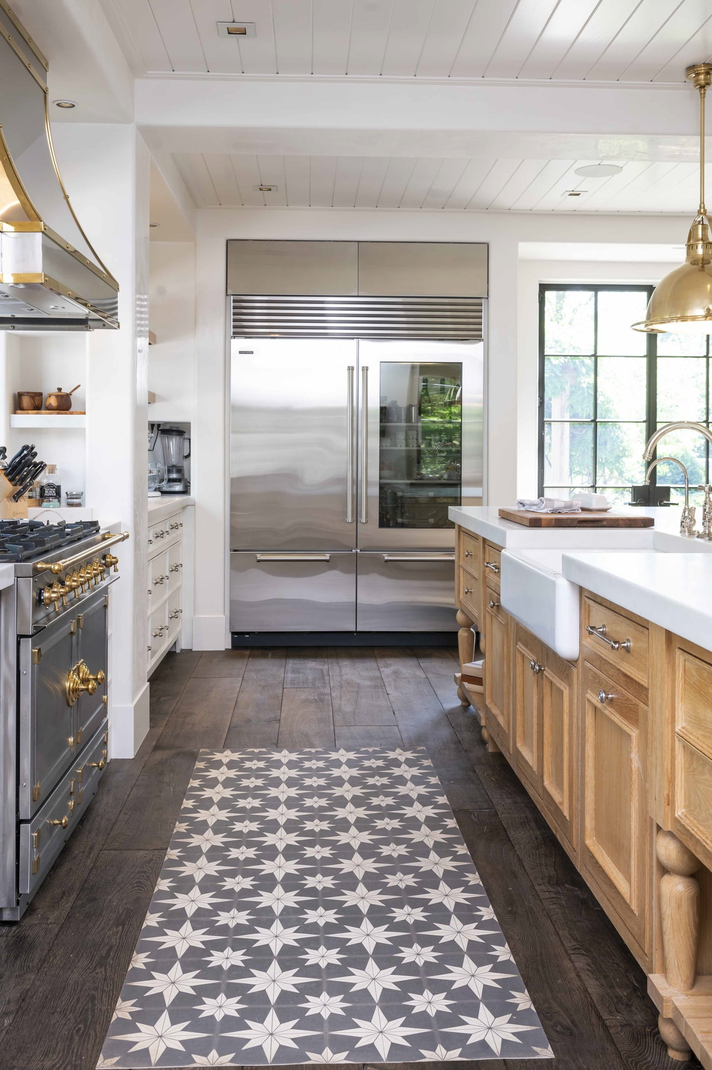 Transitional kitchen with light wood cabinetry and white marble countertops, stainless steel appliances, and dark hardwood flooring