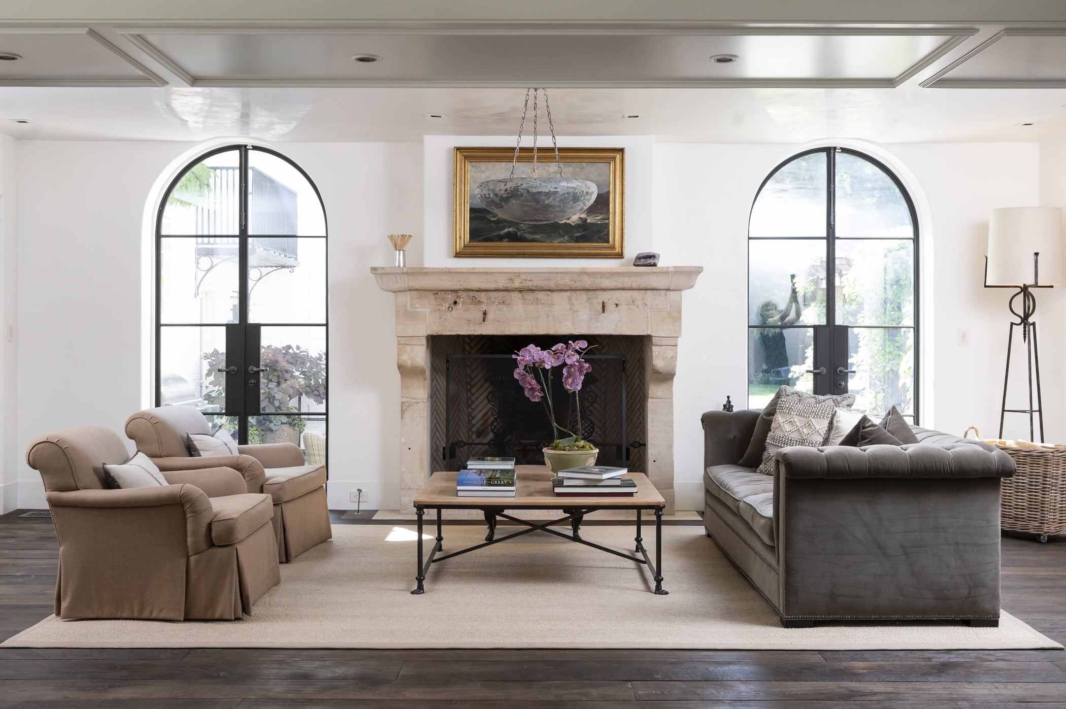 Transitional living room with dark hardwood flooring, light beige carpet, minimal furniture, floor-to-ceiling oval doors, and decorative fireplace