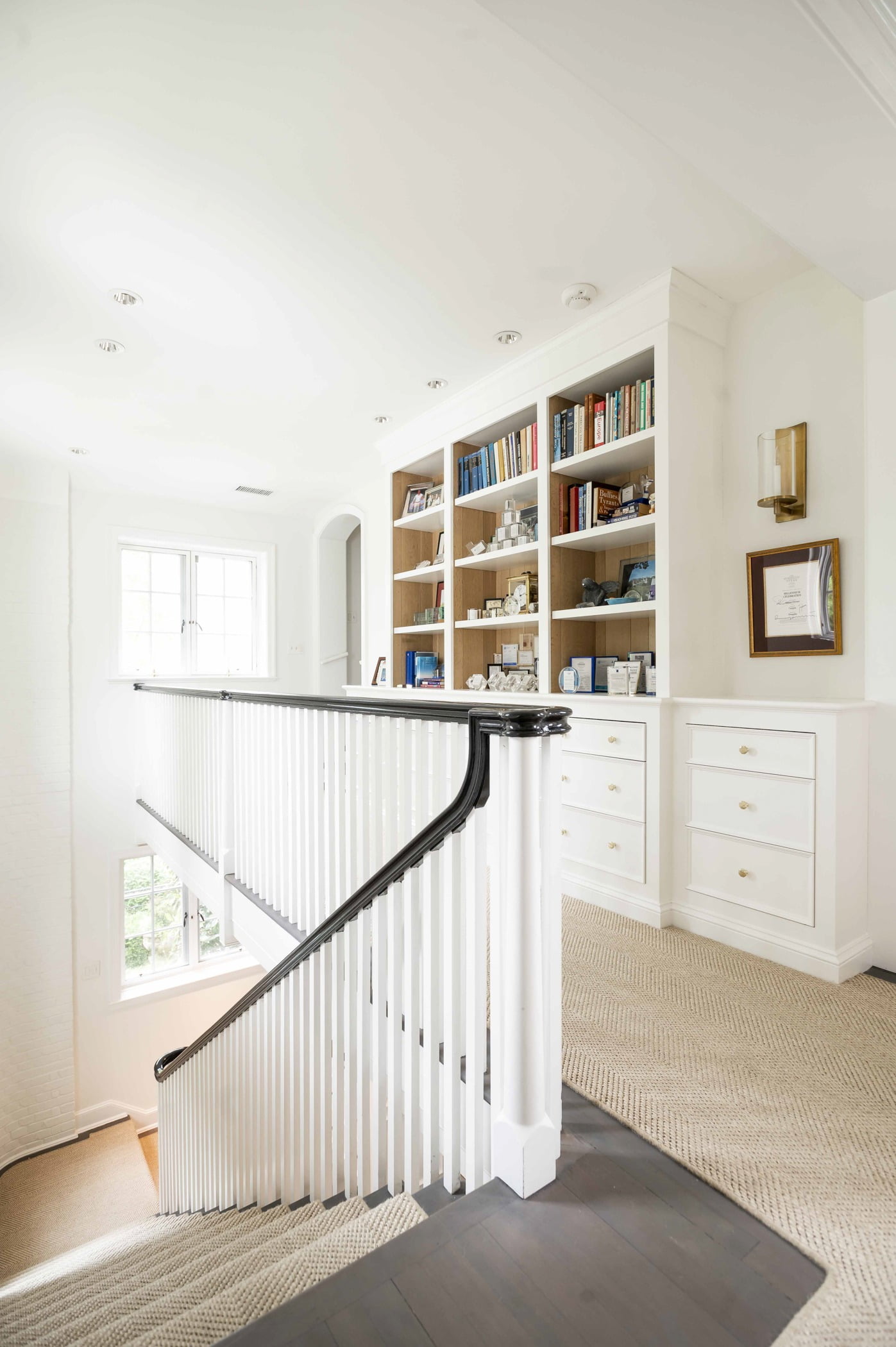 Transitional upstairs hallway, dark hardwood flooring with beige carpet, black and white wood railings