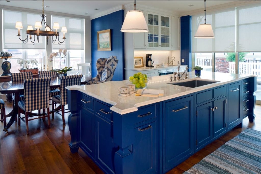 Transitional kitchen/dining room with medium hardwood flooring and custom navy island drawers and navy accent wall