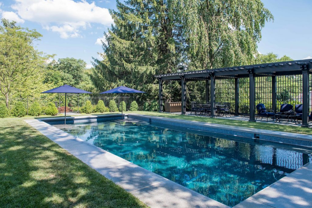 Transitional backyard pool with long dark metal pergola