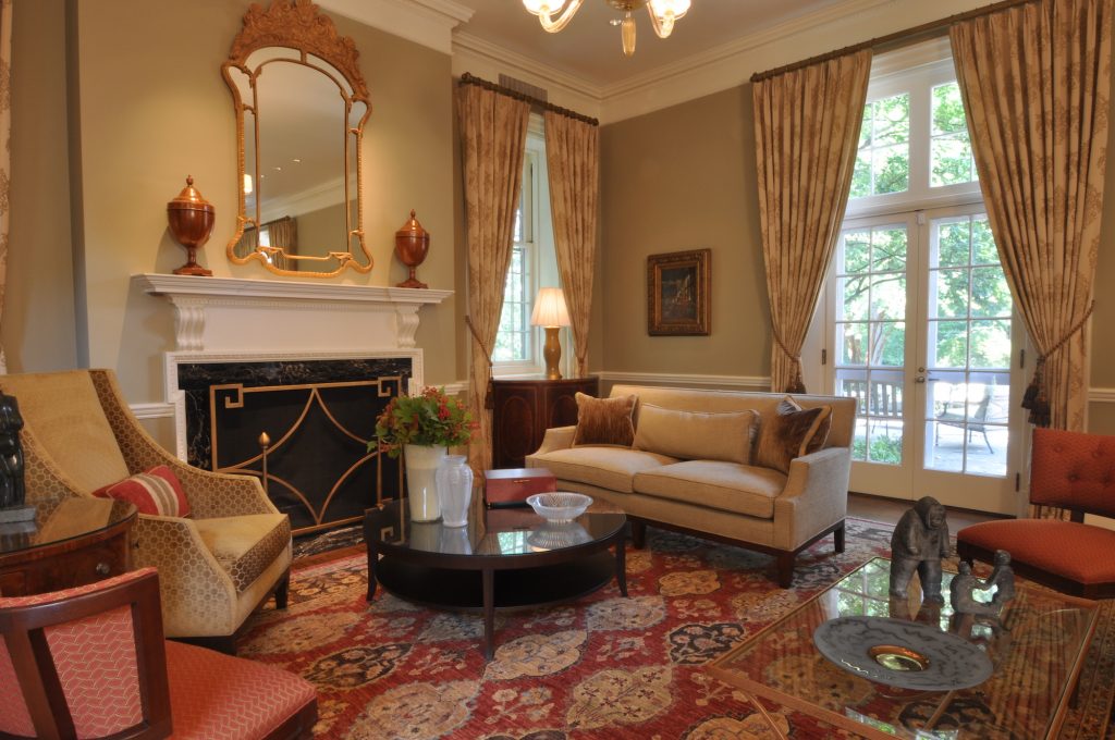 Traditional living room with ornate metalwork fireplace and mirror, decorative red carpet and matching furniture