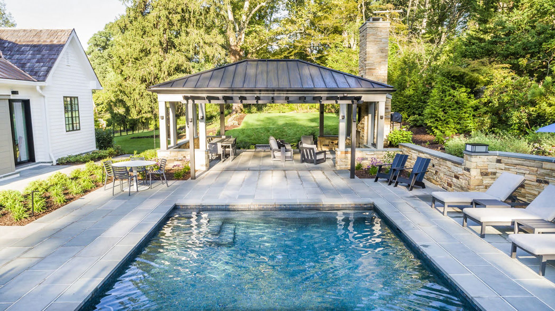 Transitional backyard patio bar and pool house with concrete pavers and cobblestone accented retaining walls (Different view)