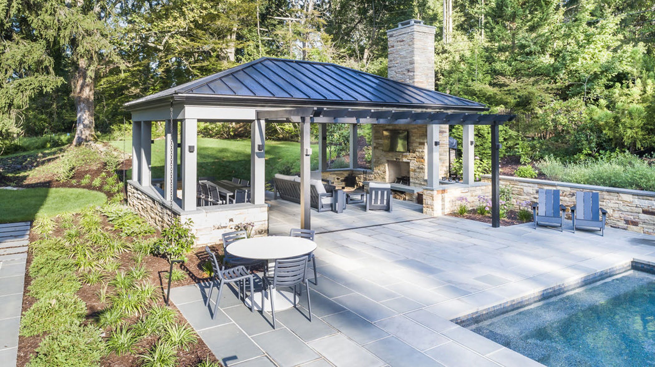 Transitional backyard patio bar and pergola with concrete pavers and cobblestone accented retaining walls