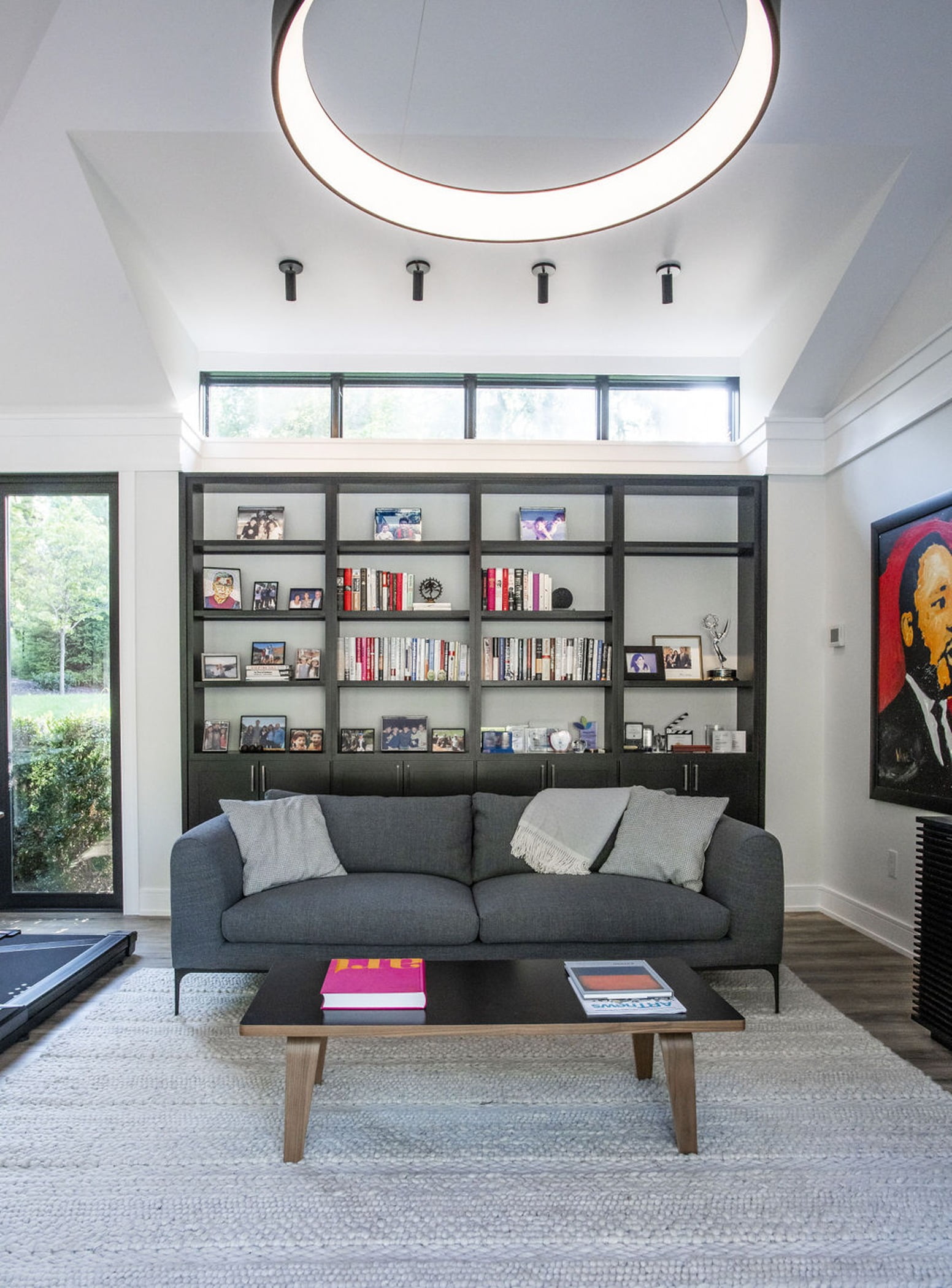 Modern office space with floor to ceiling windows, built in wall shelves and minimalistic furniture (Couch view)