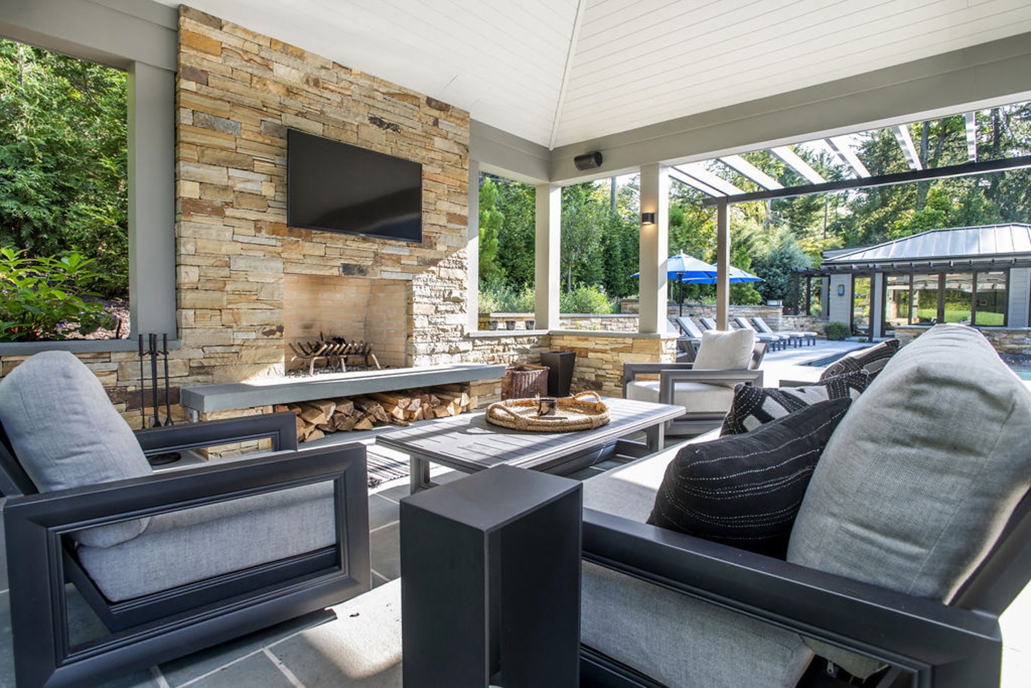 Transitional backyard patio bar and poolhouse with concrete pavers and cobblestone accented retaining walls (sitting area view)