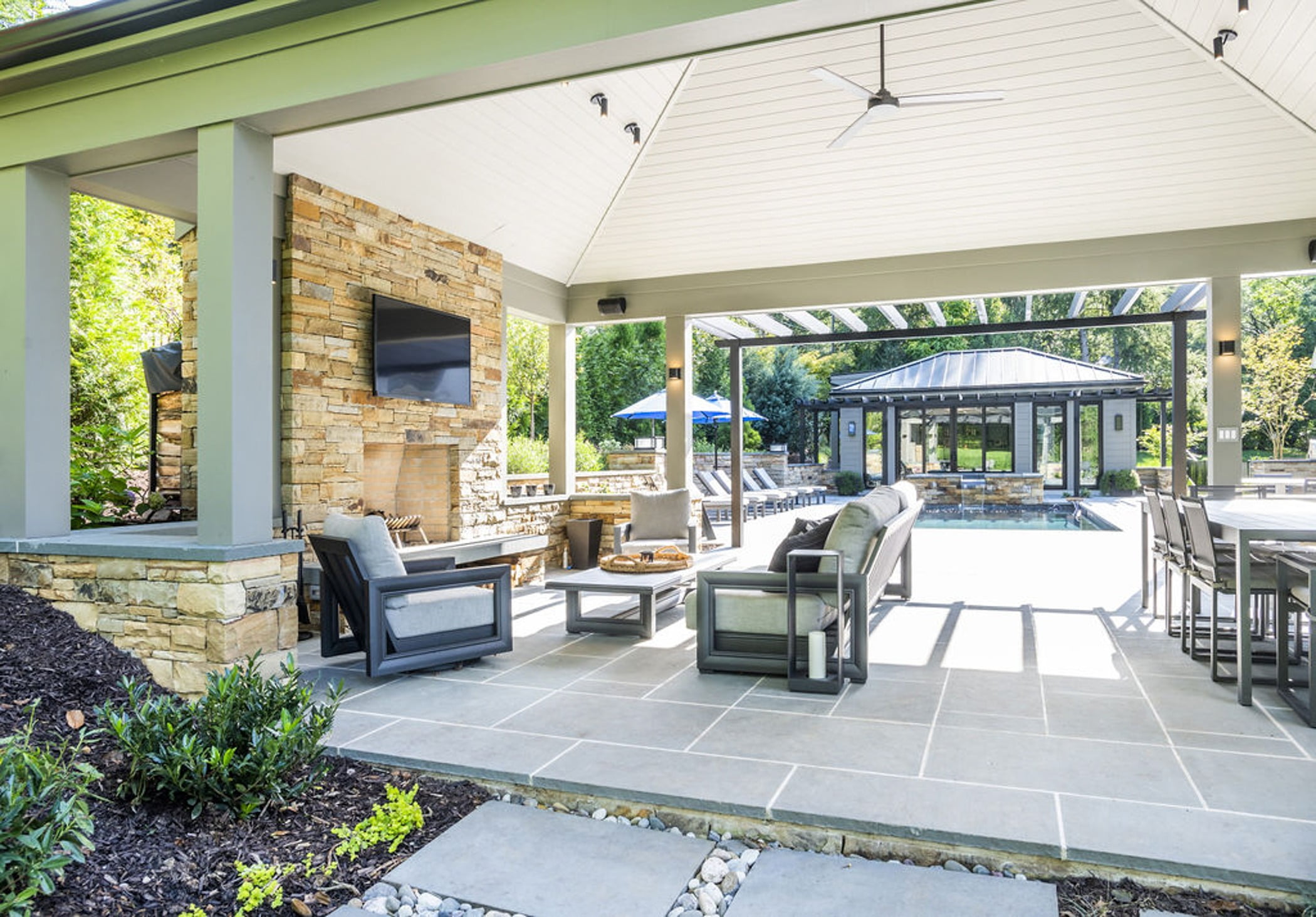 Transitional backyard patio bar and poolhouse with concrete pavers and cobblestone accented retaining walls and hot tub