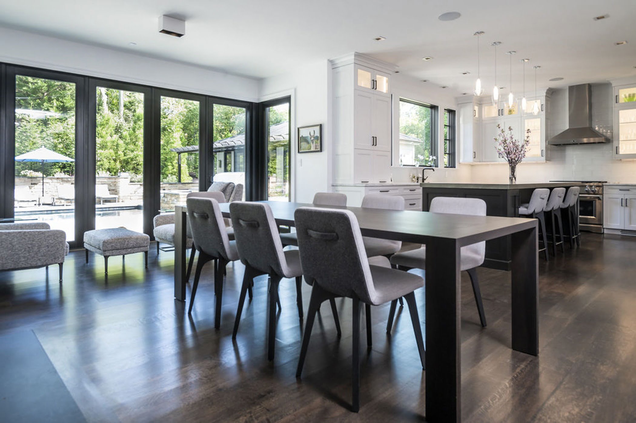 Modern dining area with sleek dark hardwood table and flooring, and matching dining chairs