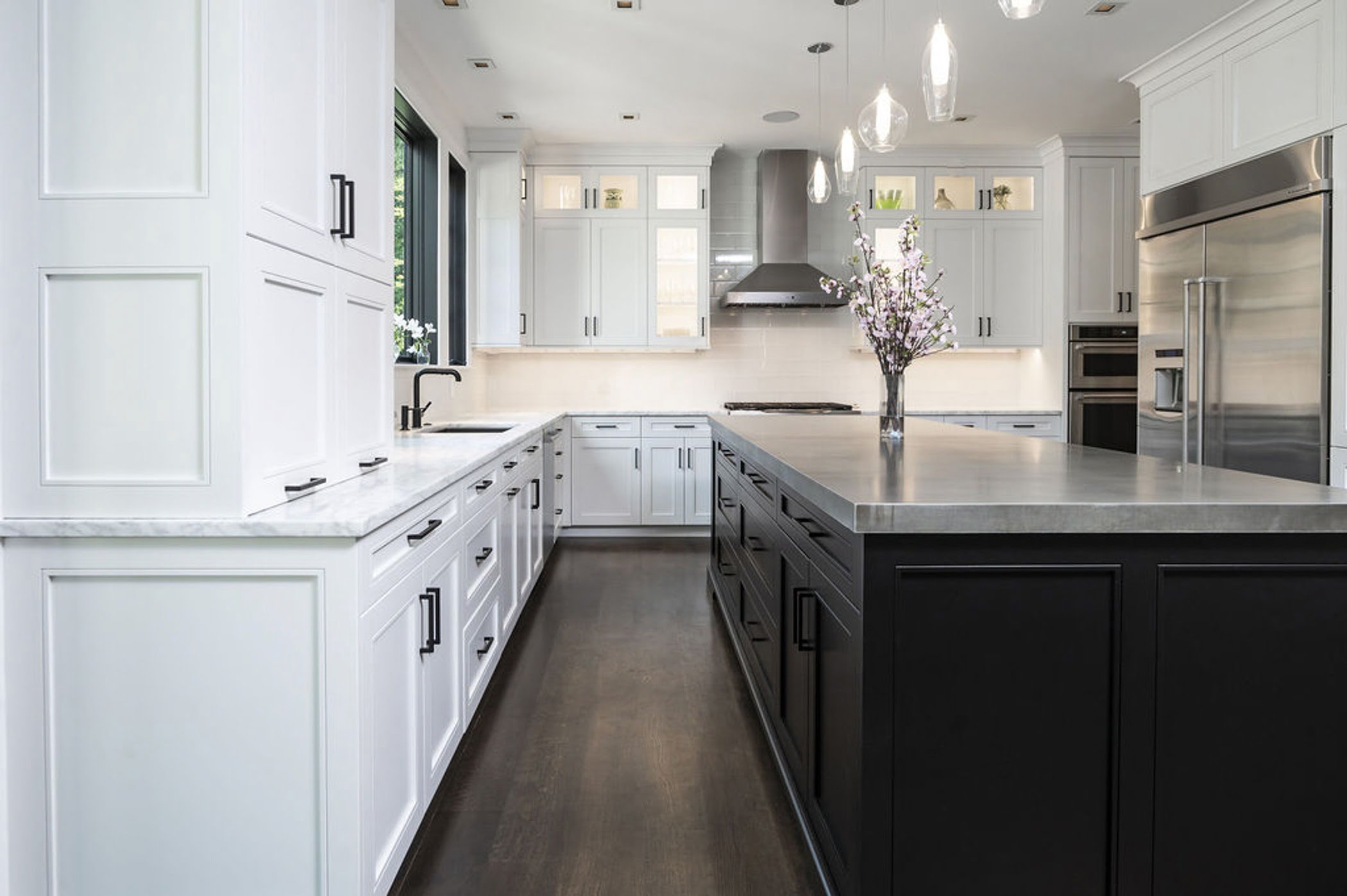 Modern kitchen remodel with an open concept layout including white cabinetry, marble countertop and a dark wood center island (Different view)