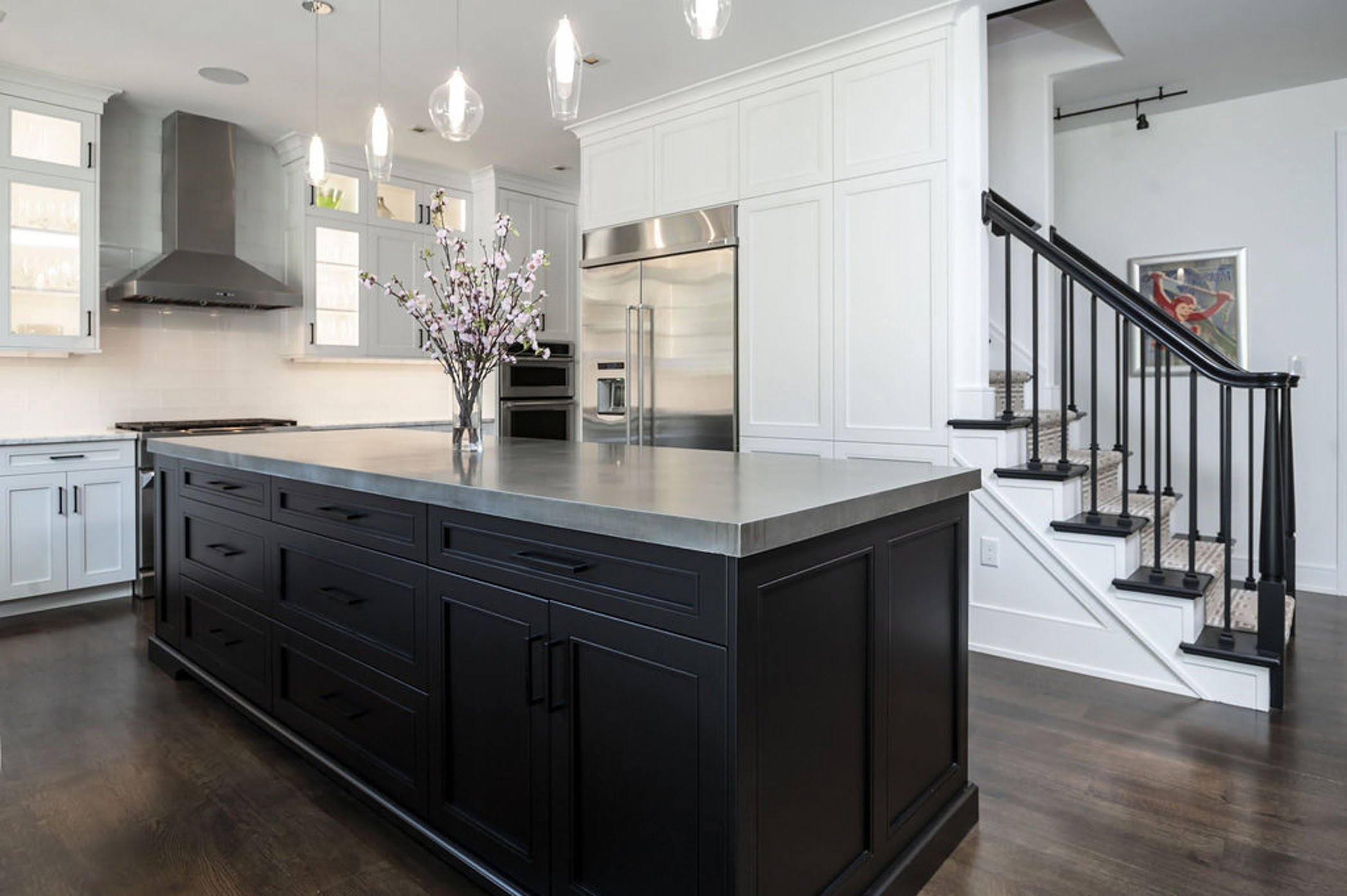 Modern kitchen remodel with an open concept layout including white cabinetry, marble countertop and a dark wood center island (2)