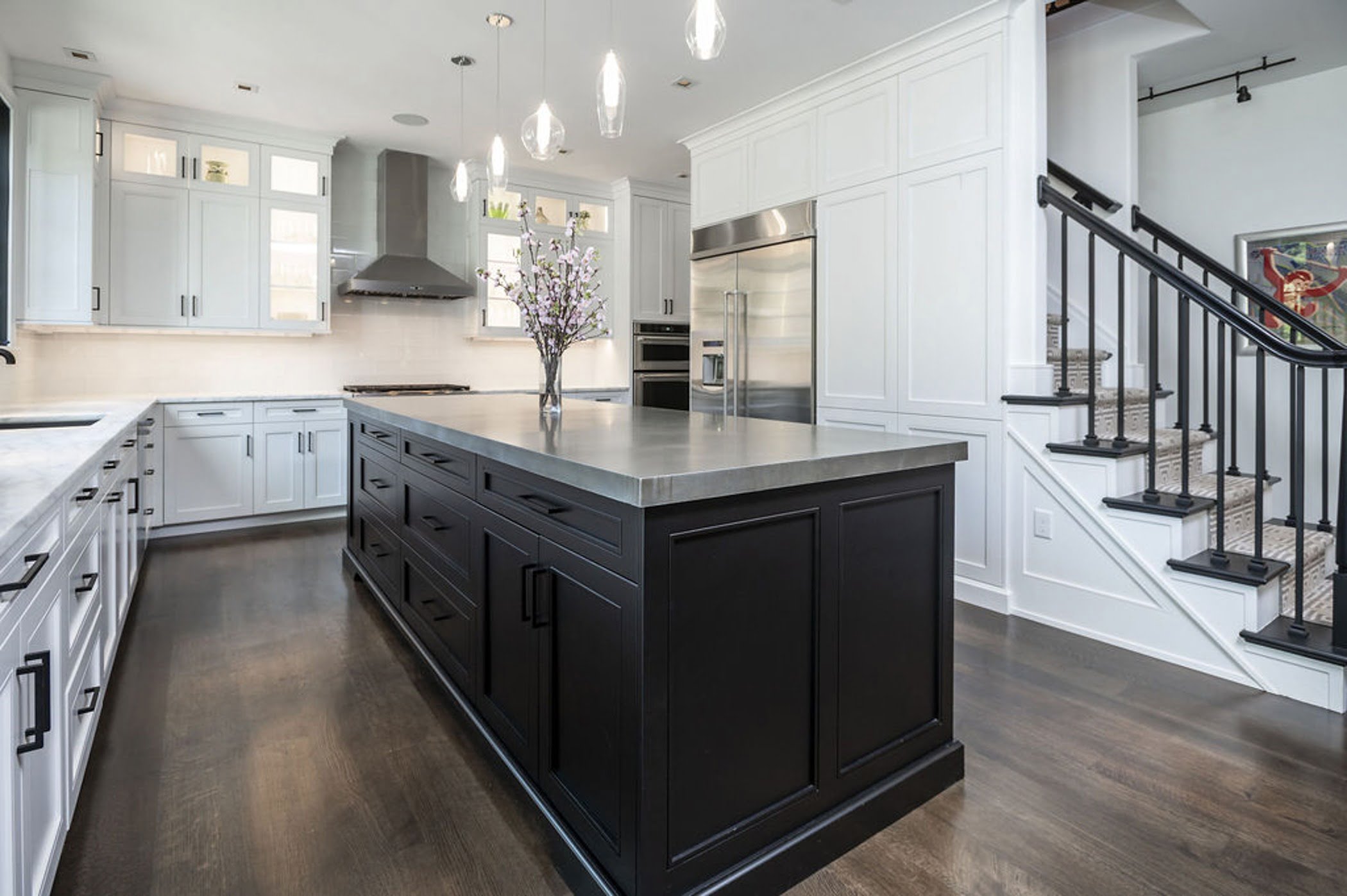 Modern kitchen remodel with an open concept layout including white cabinetry, marble countertop and a dark wood center island.