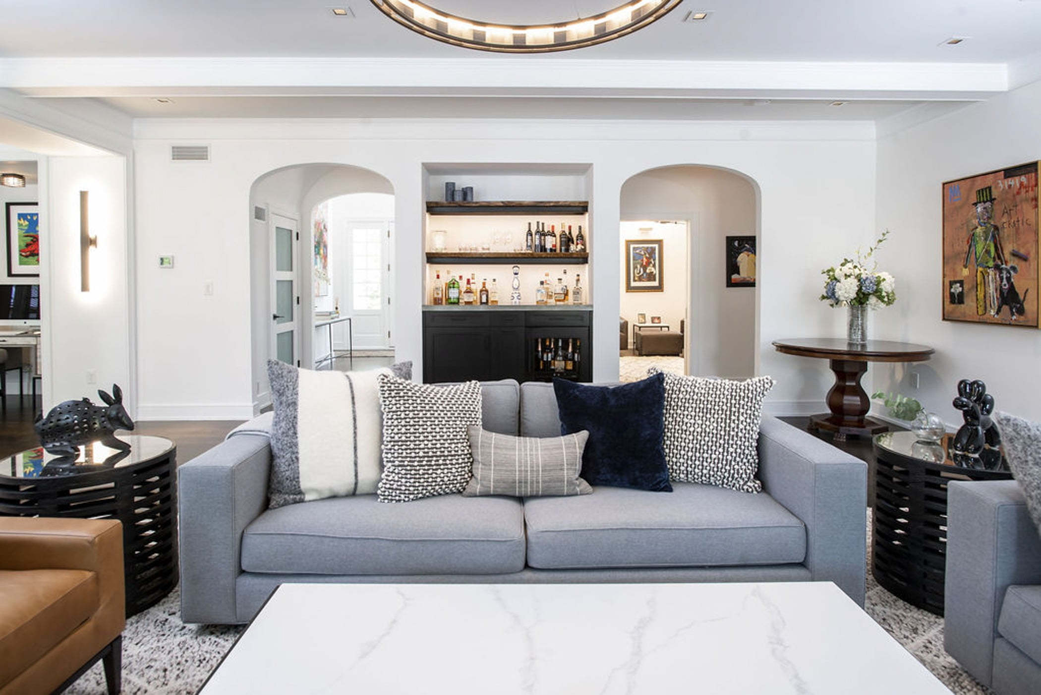 Modern family room with marble coffee table, black steel-framed tv and fireplace, and sleek furniture (Couch view)