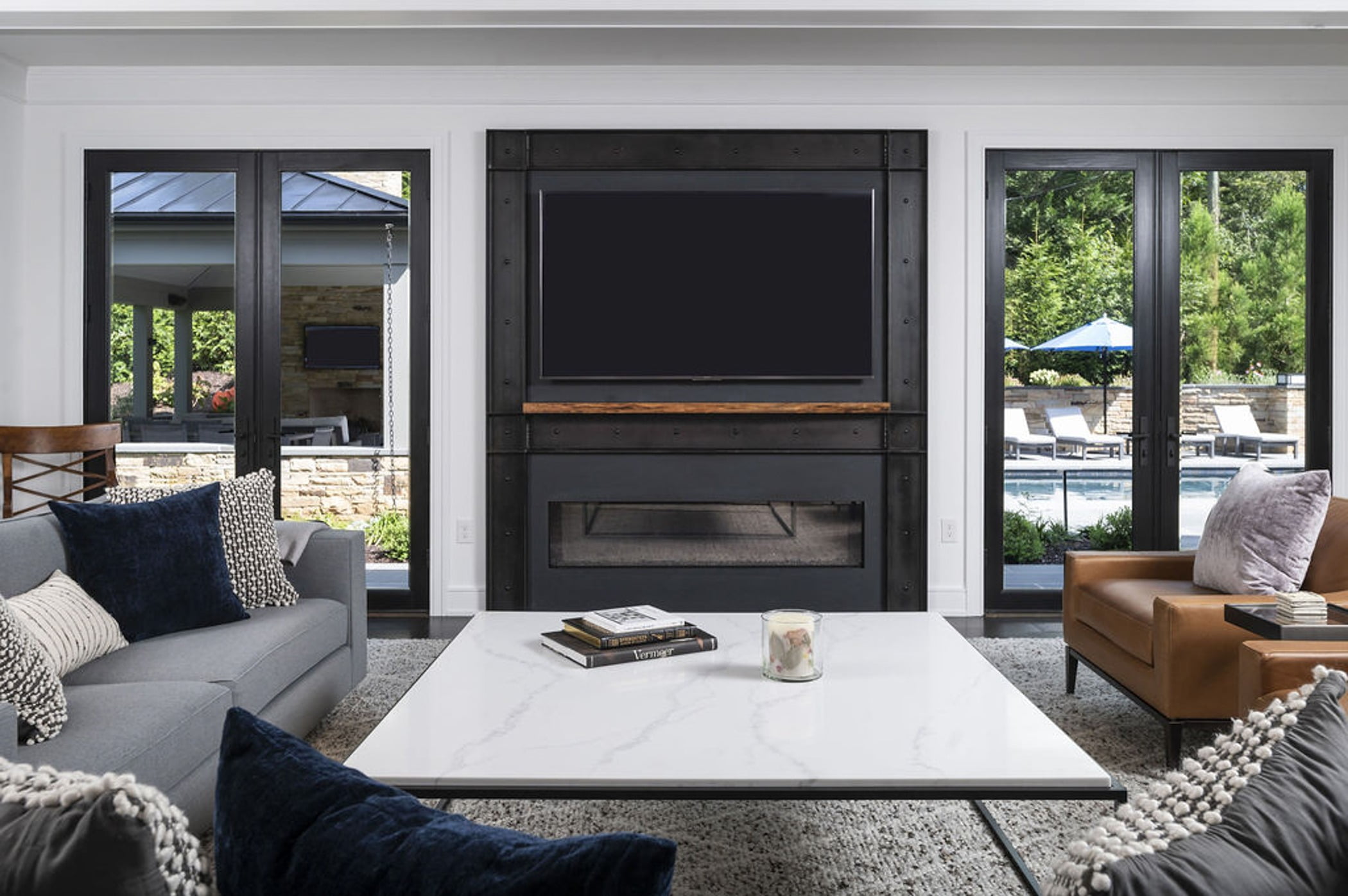 Modern family room with marble coffee table, black steel-framed tv and fireplace, and sleek furniture