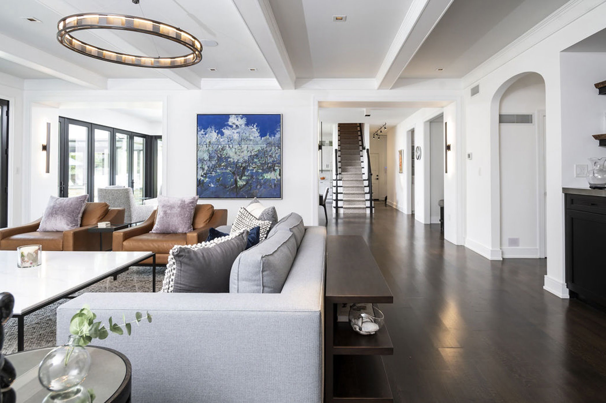 Modern family room with dark hardwood flooring and cabinetry, all white wall color, and minimal color palette for furniture