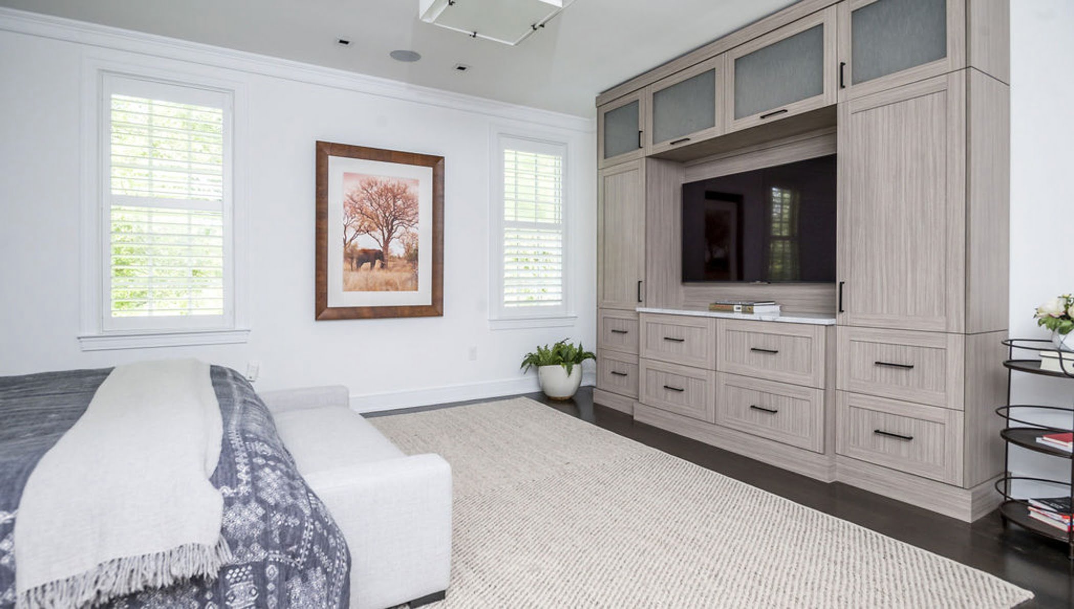 Modern bedroom remodel with a wall-to-wall media console in a light wood color with black drawer pulls.