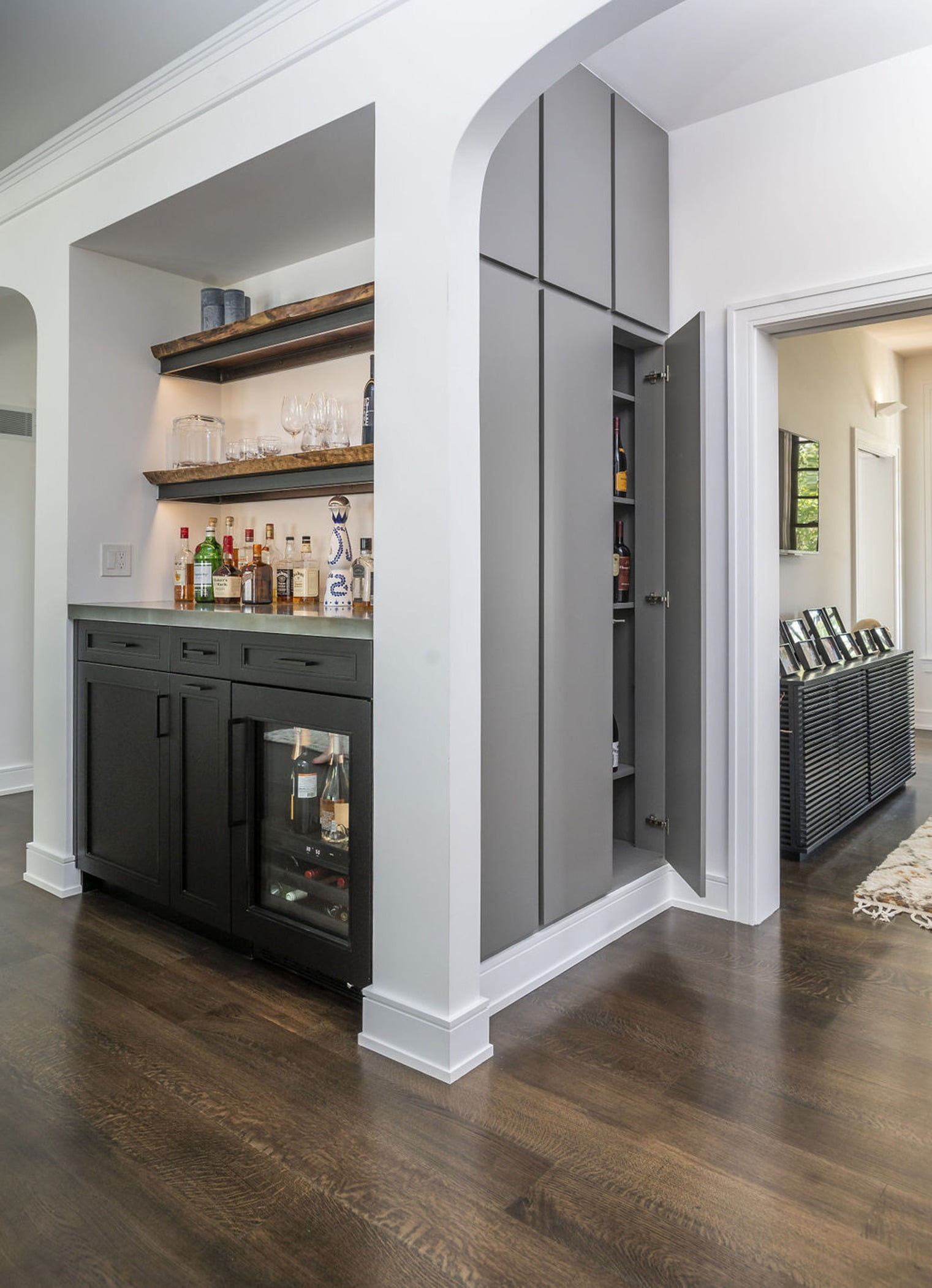 Living room and kitchen space with built in wall cabinetry and a custom, built-in bar