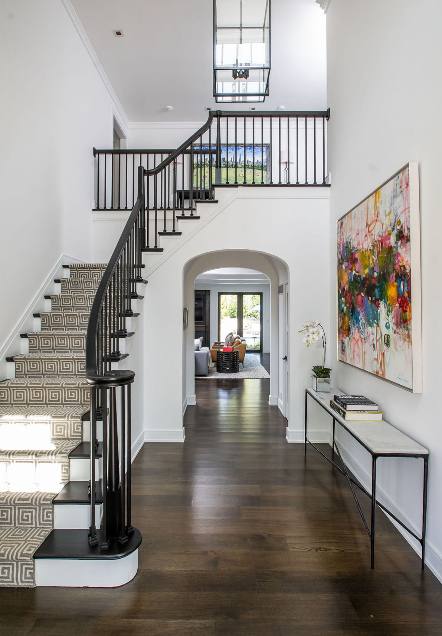 Open-concept entryway with stairs, dark wood floors and arched doorways in a modern home
