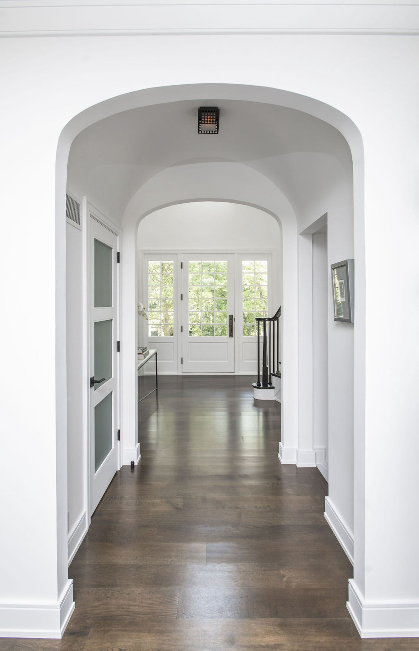 Transitional interior archway with dark hardwood flooring and clean white walls