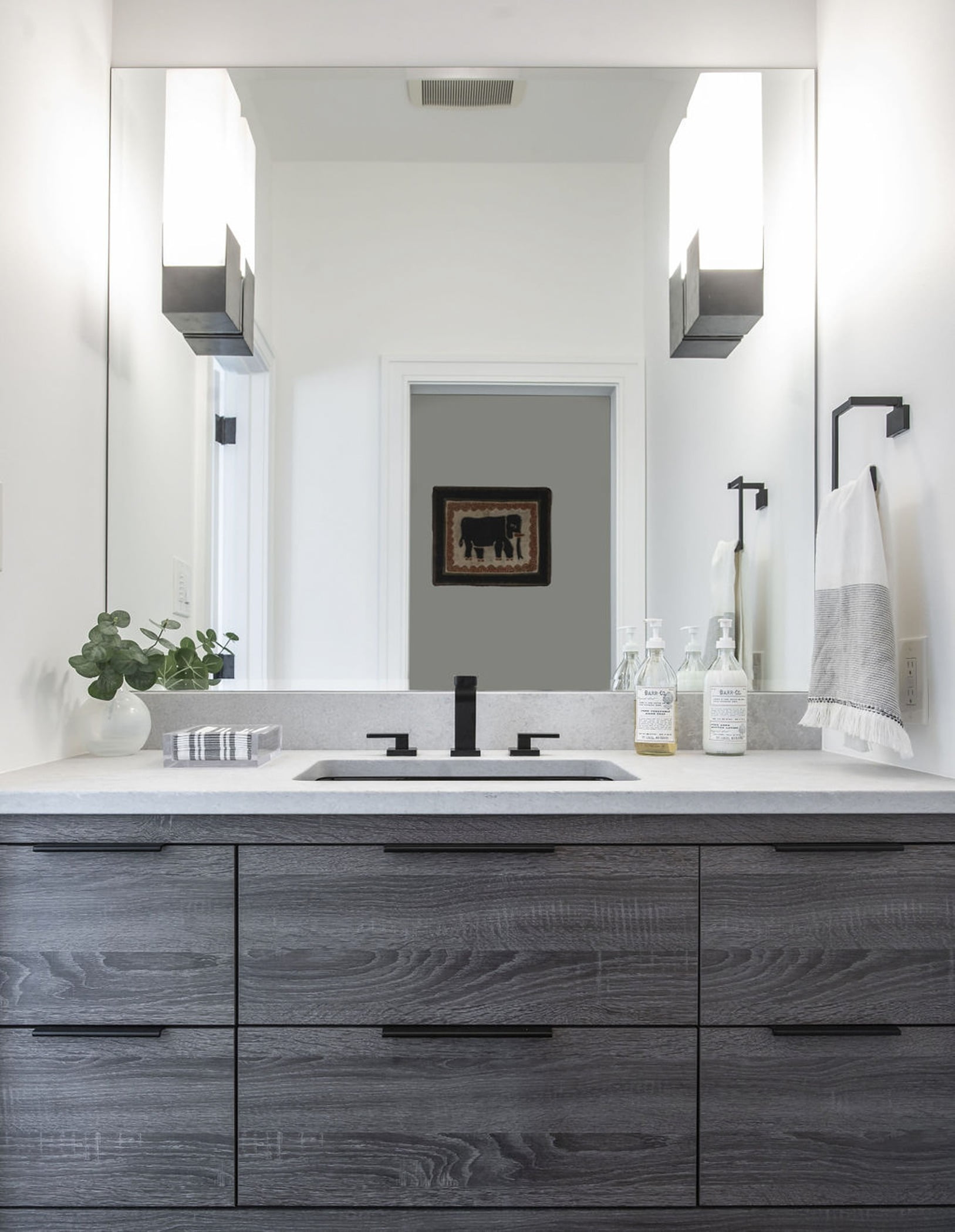 Modern style bathroom sink with dark grey cabinetry, marble countertops, and sleek black handles and faucet