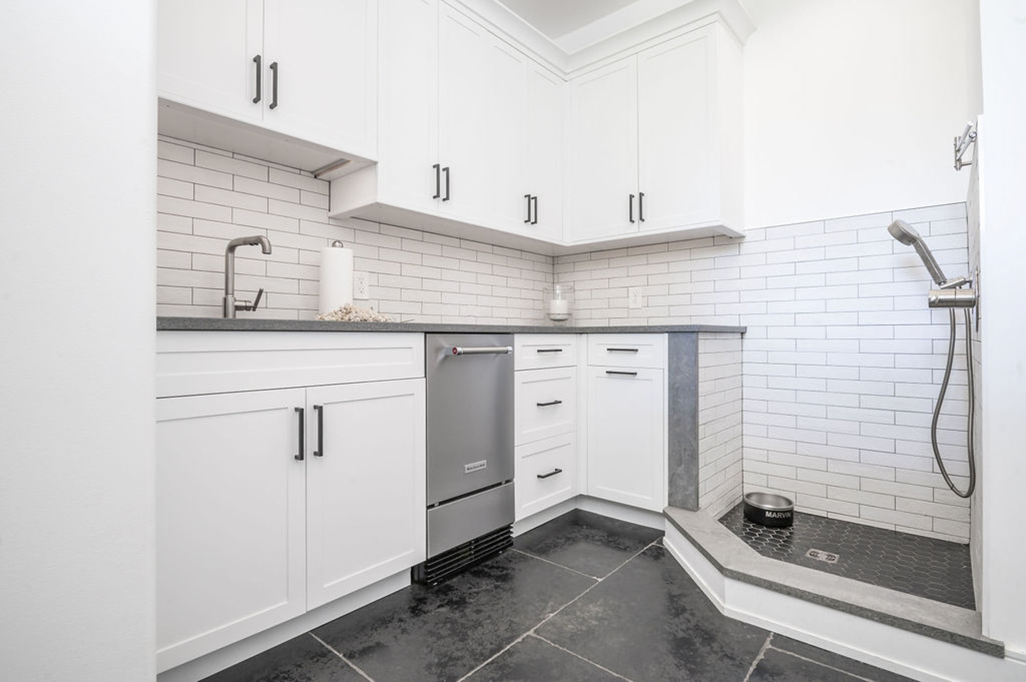 Remodeled mudroom with a kitchenette, white cabinetry, gray countertops and a small dog shower with honeycomb and subway tile