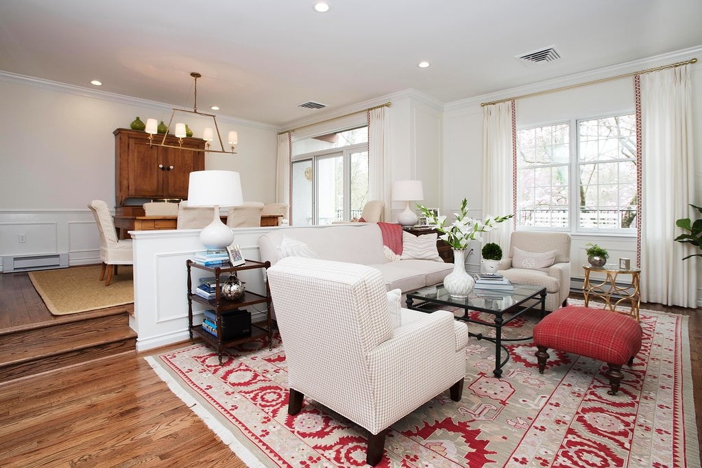 Transitional living and dining rooms with medium hardwood flooring, minimal cream furniture, and patterned carpet accented red